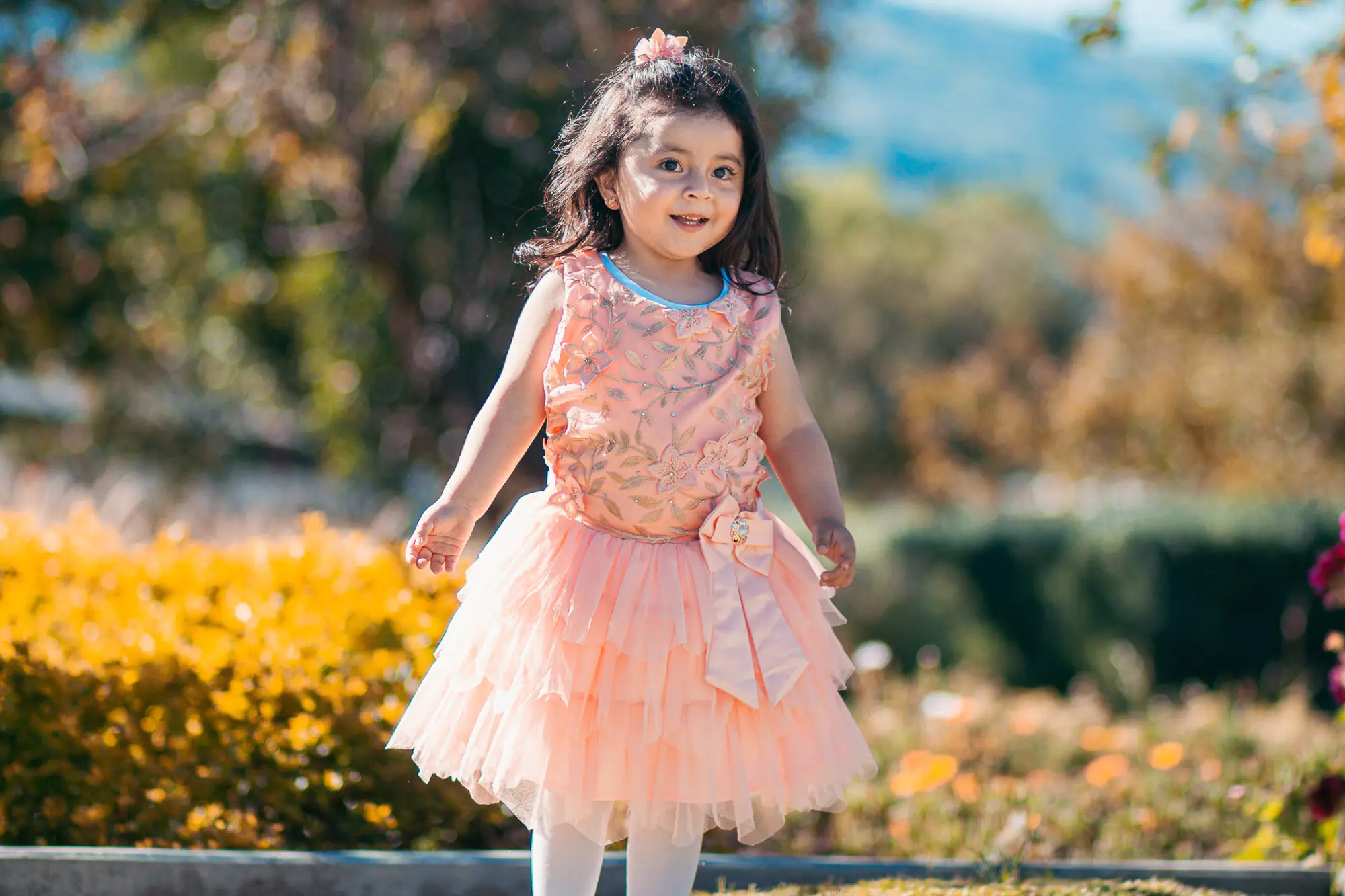Niña sonriendo en un jardín durante sesión infantil
