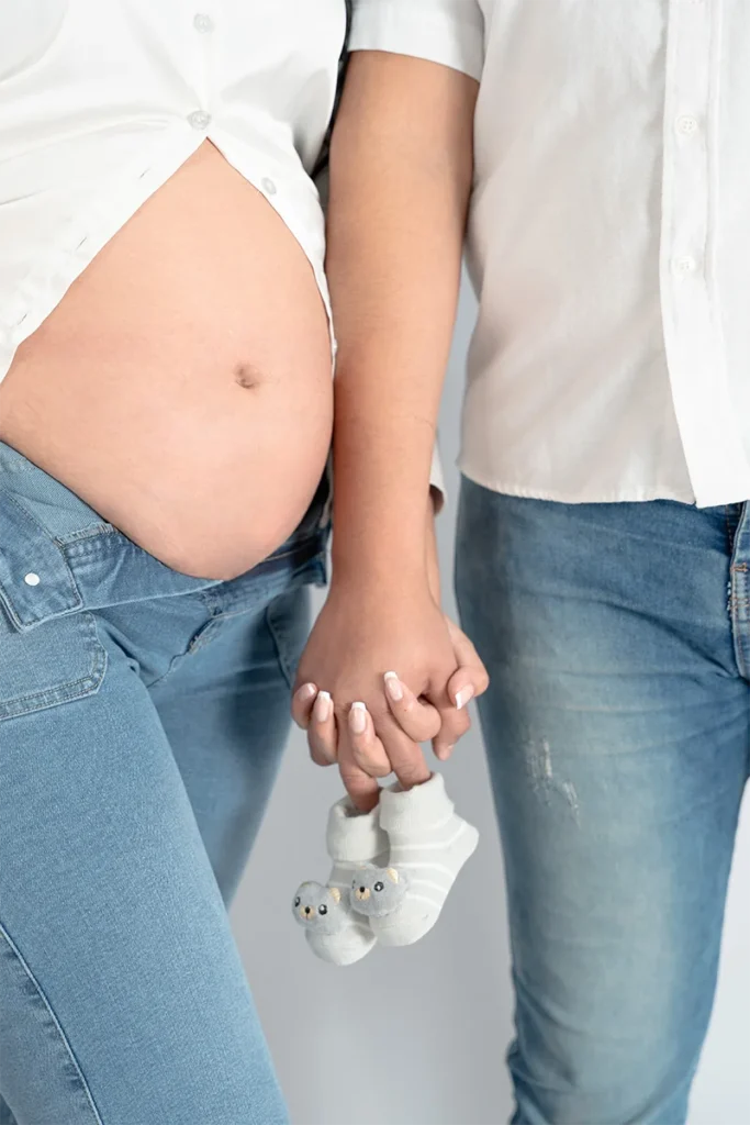 Una pareja de esposos tomados de la mano y su esposa está embarazada